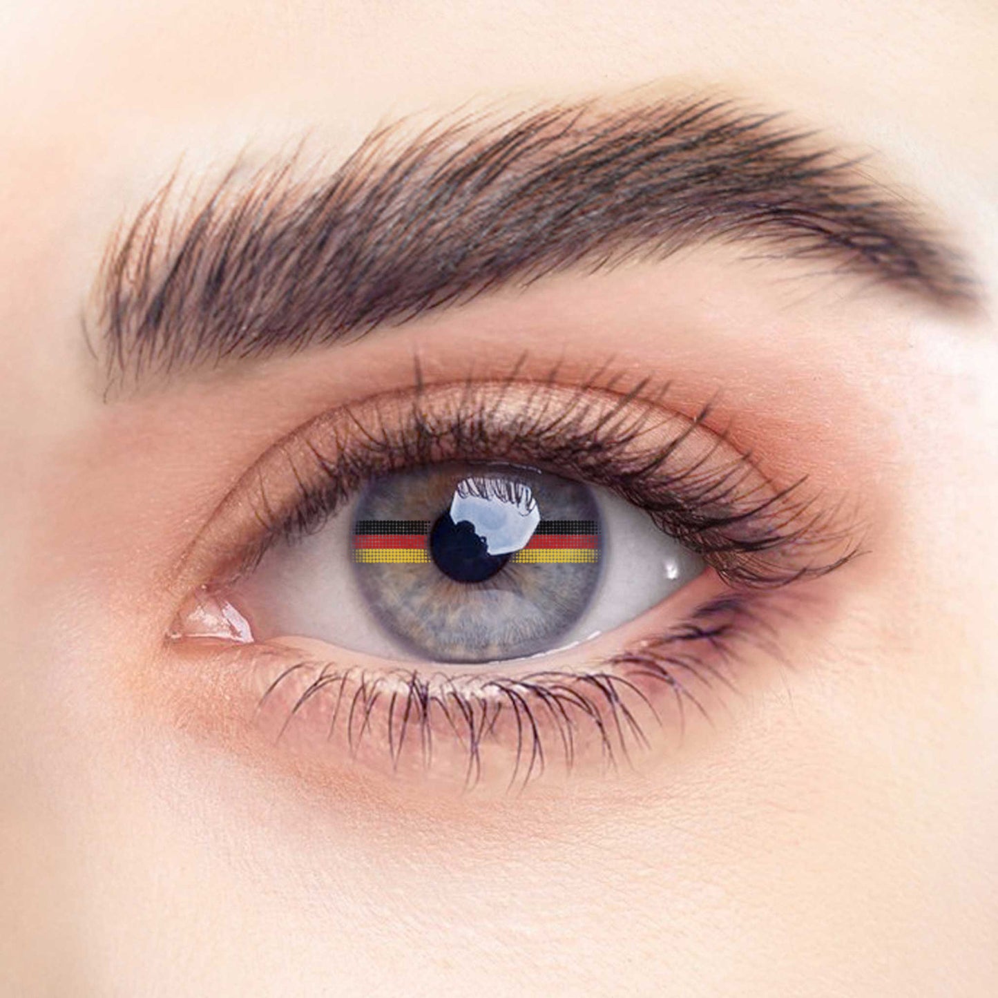 Rehlein Premium Beauty Linsen in der "Germany"-Edition. Transparente Monatslinsen ohne Sehstärke mit Flaggenmotiv. Kontaktlinsen mit dekorativer Deutschlandflagge für den täglichen Gebrauch. Nahaufnahme am Auge.