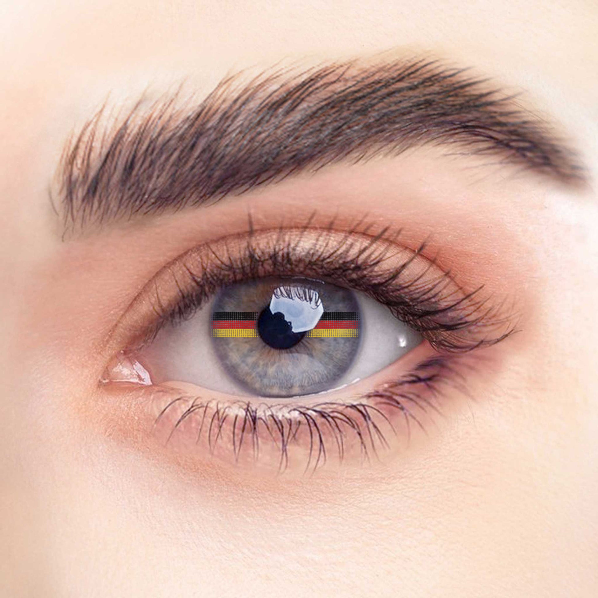 Rehlein Premium Beauty Linsen in der "Germany"-Edition. Transparente Monatslinsen ohne Sehstärke mit Flaggenmotiv. Kontaktlinsen mit dekorativer Deutschlandflagge für den täglichen Gebrauch. Nahaufnahme am Auge.